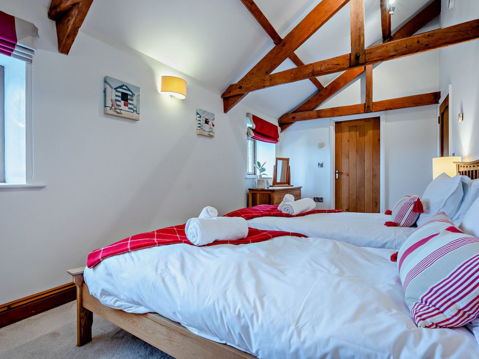 A bedroom with two beds and a wooden table at Middle Hill in Marhamchurch