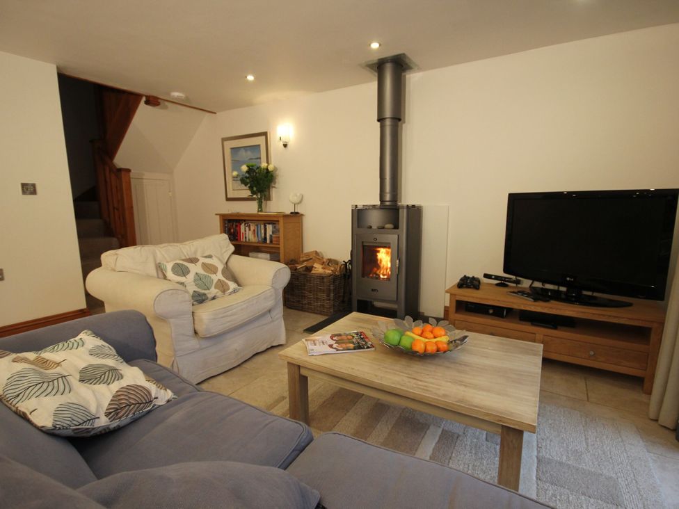 A living room with a wood stove and sofa at Sand Parks in Marhamchurch