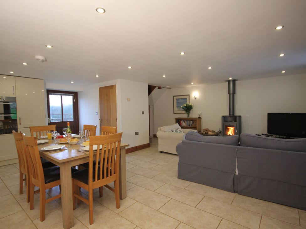 A living room and dining area with a stove and television at Sand Parks Marhamchurch