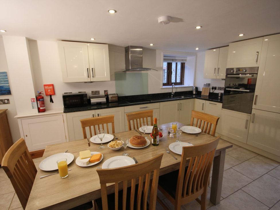 A kitchen with a dining table set for a meal at Sand Parks, Marhamchurch