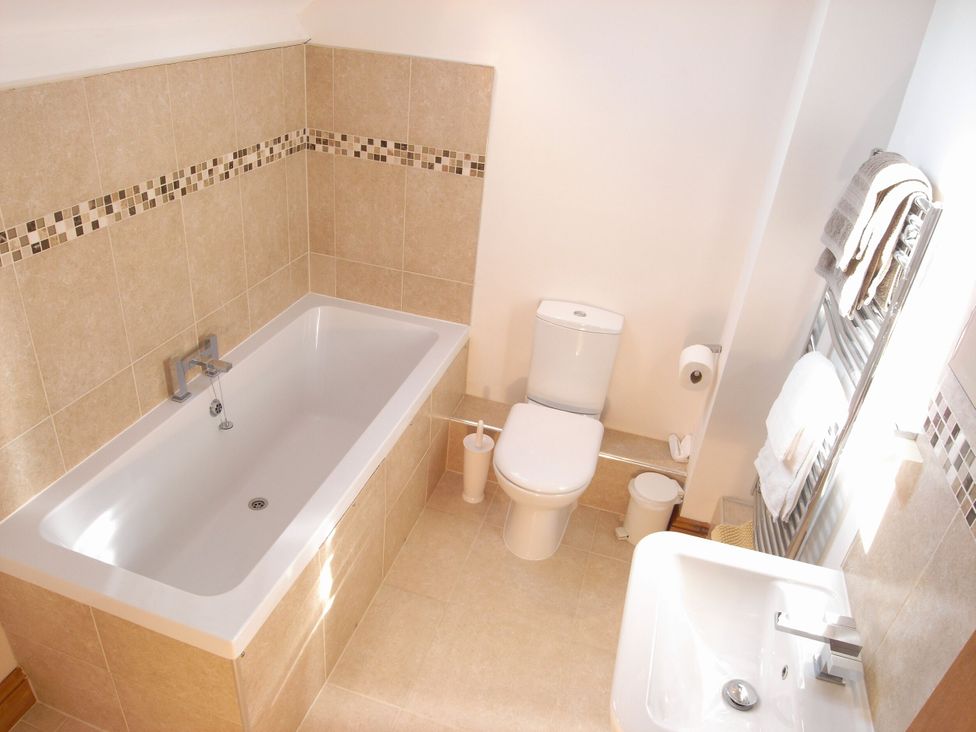 A bathroom with a bathtub, toilet, and sink at Sand Parks in Marhamchurch