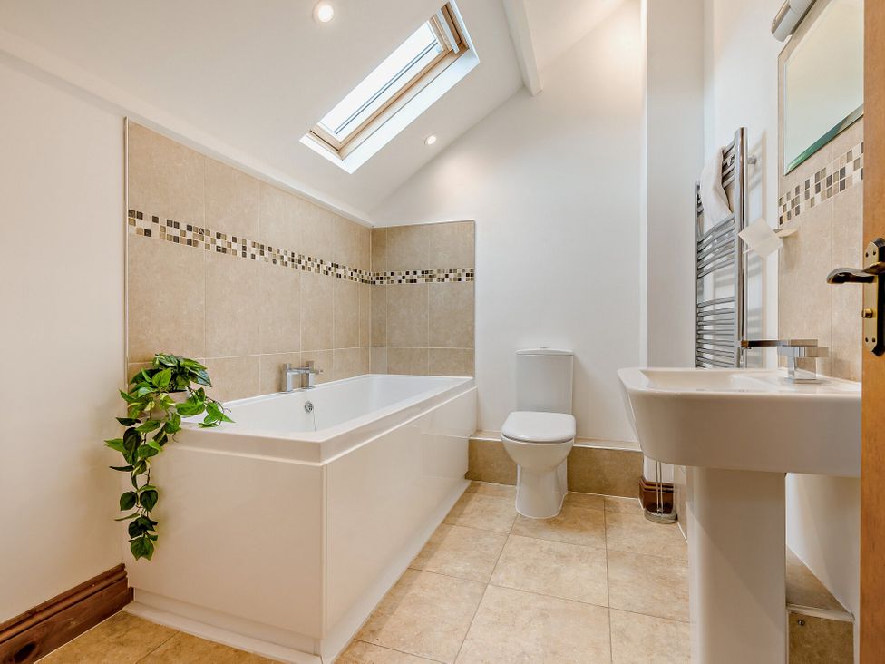 A bathroom with a bathtub, toilet and sink at Sand Parks in Marhamchurch
