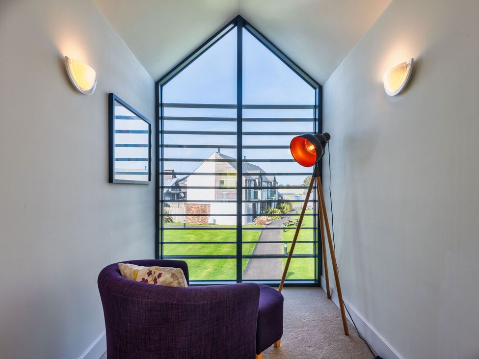 A seating area with a lamp and mirror at Venners in Marhamchurch