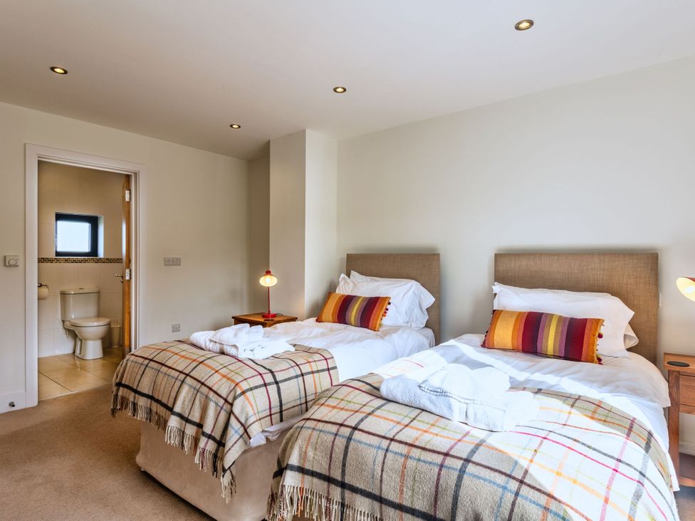 A bedroom with twin beds and an adjoining bathroom at Venners in Marhamchurch