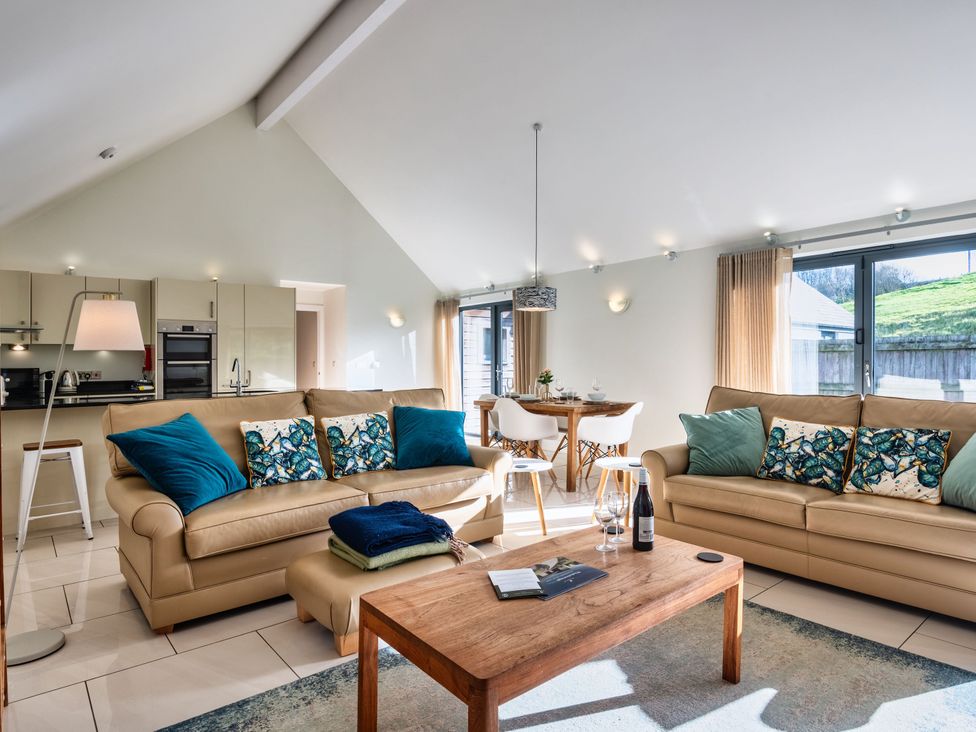 A living room with a sofa and dining table at Warrens Spa in Marhamchurch