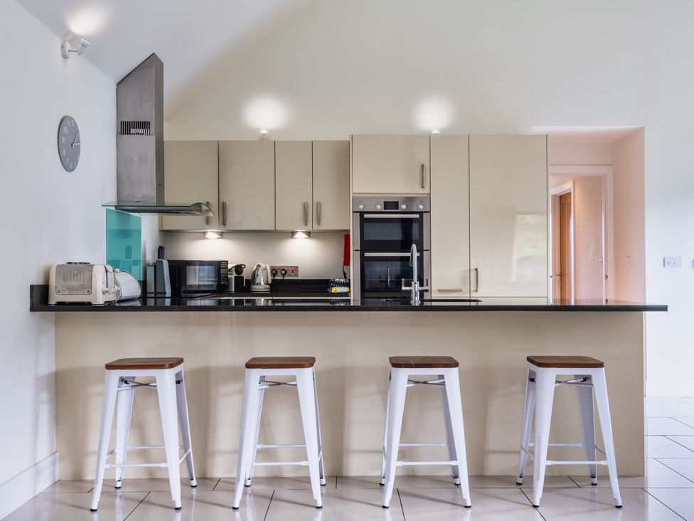 A kitchen with bar stools and appliances at Warrens Spa in Marhamchurch