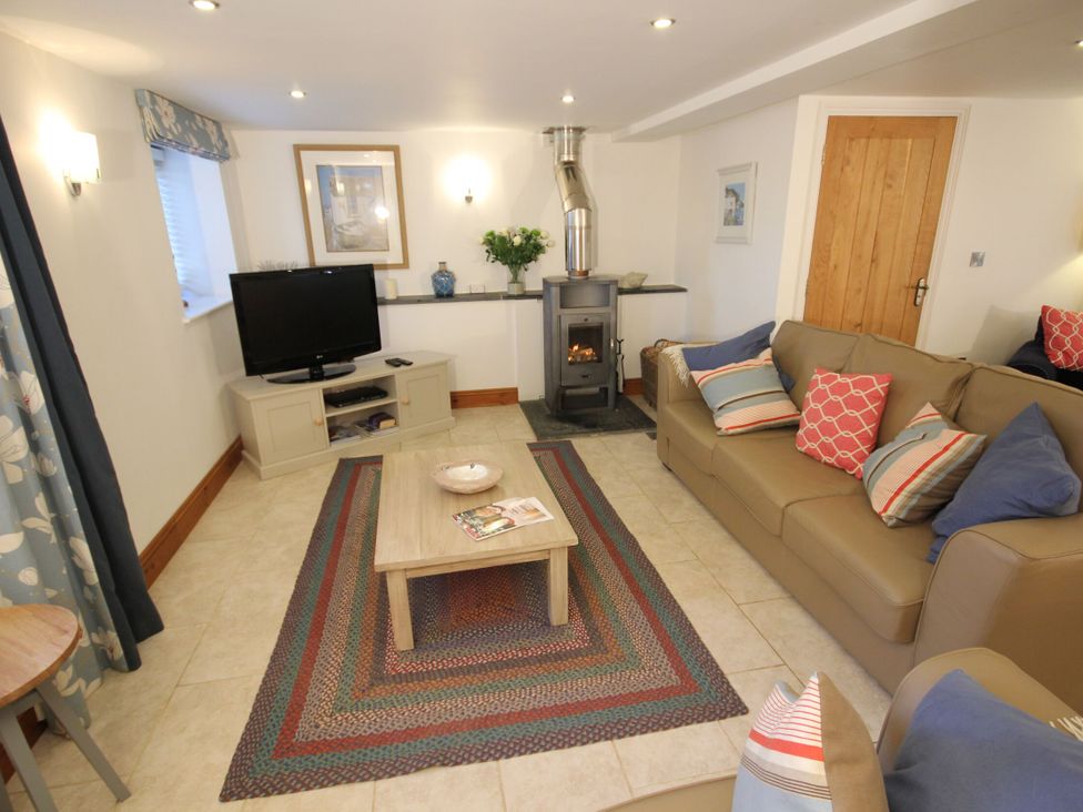 A living room with a television and a wood stove at Westcotts in Marhamchurch