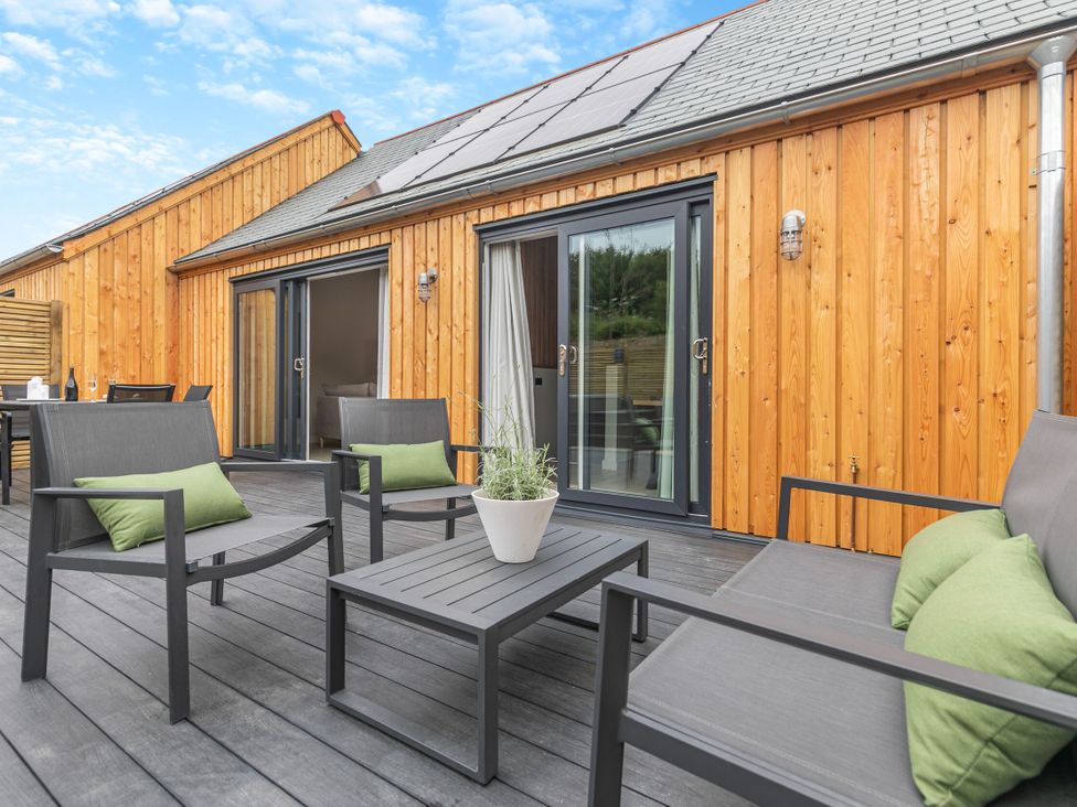 An outdoor patio with chairs and a table at Gwari Spa Barn 2.0 Marhamchurch