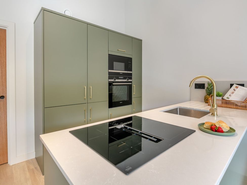 A kitchen with green cabinets and a stove at Gwari Spa Barn 2.0 in Marhamchurch
