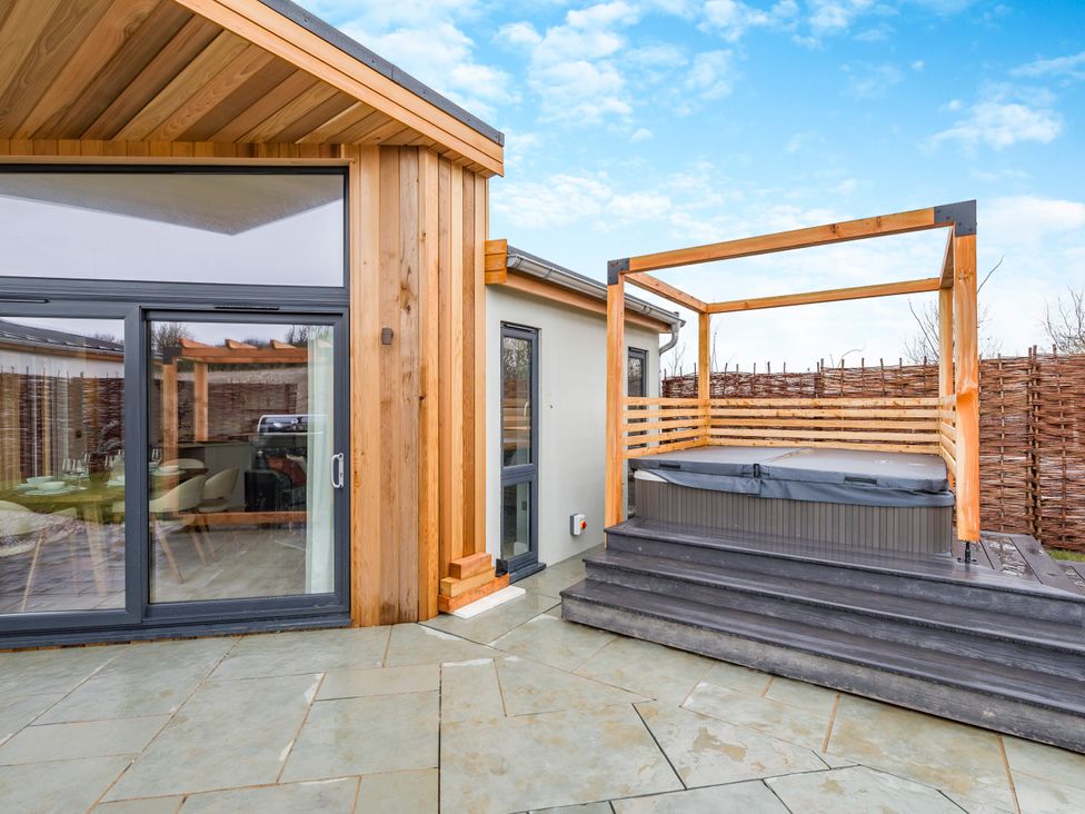An outdoor area featuring a hot tub and a wooden frame at Trelowen 2.0 Spa Marhamchurch