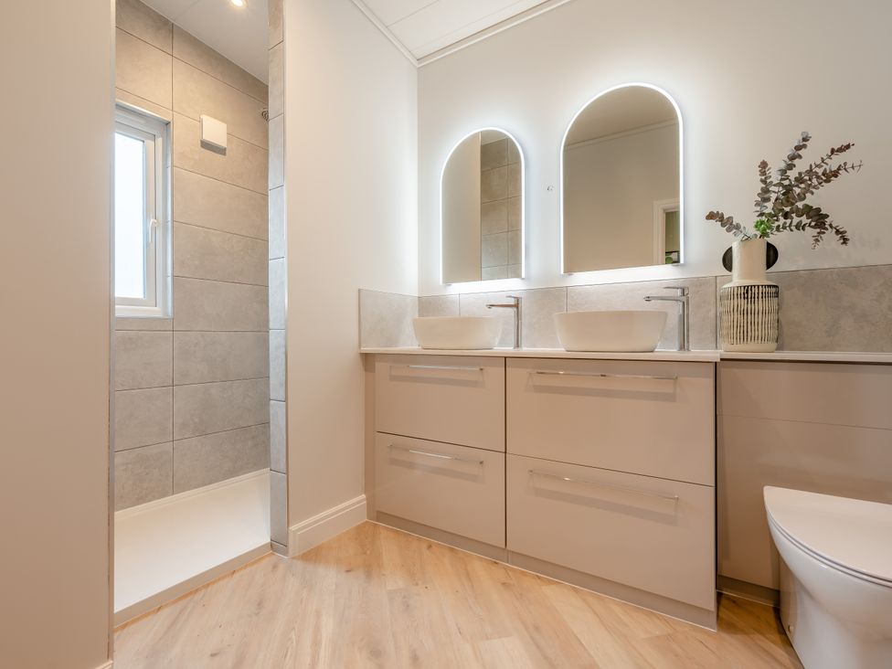A bathroom with sinks and a shower at Trelowen 2.0 Spa Marhamchurch