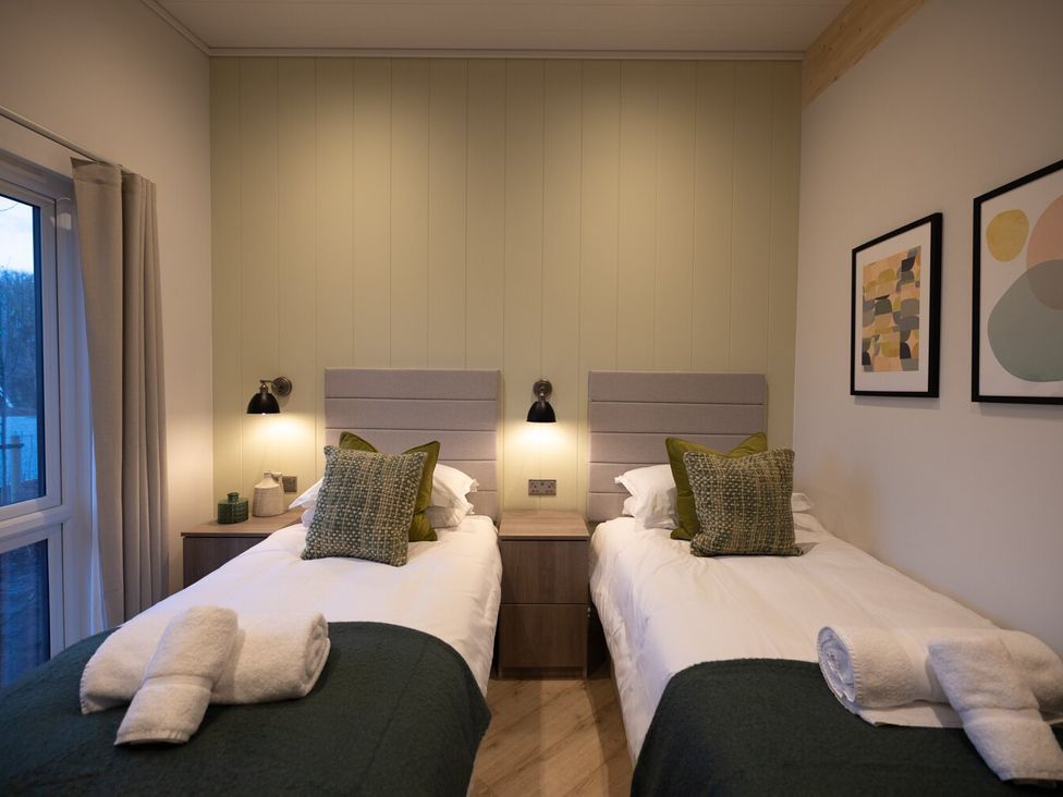 A bedroom with twin beds and artwork on the wall at Trelowen 2.0 Spa in Marhamchurch