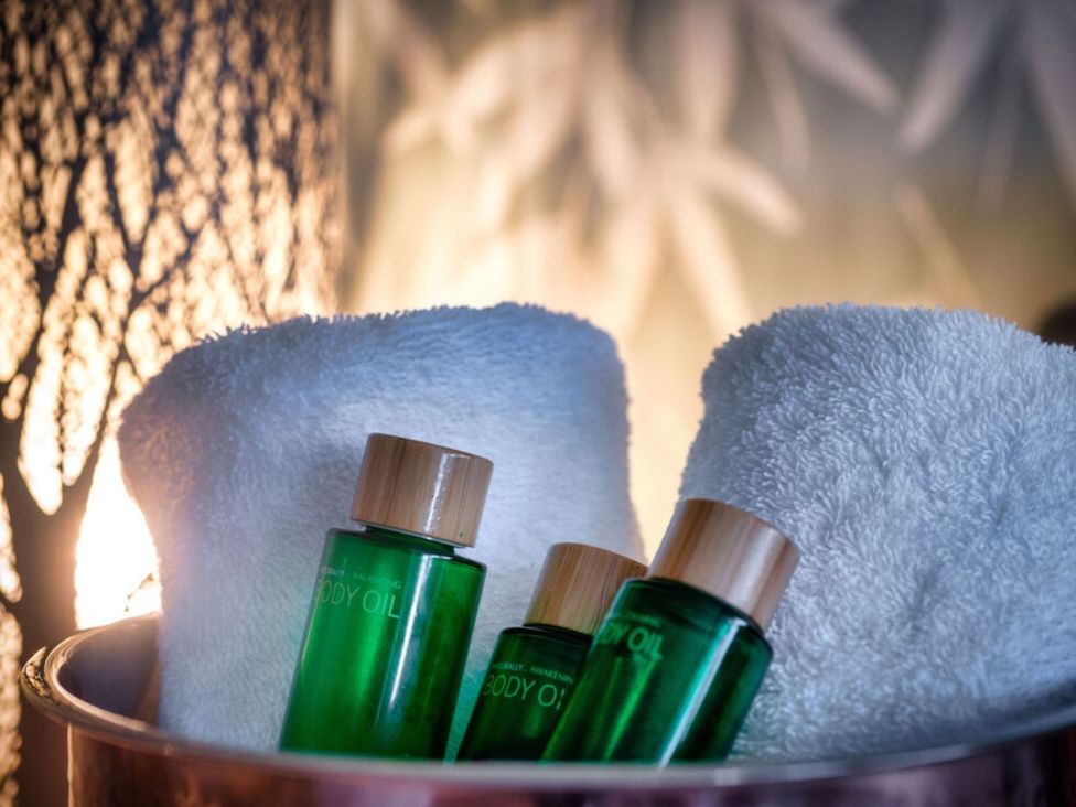 A spa setting with body oil bottles and towels at Trelowen 2.0 Spa in Marhamchurch