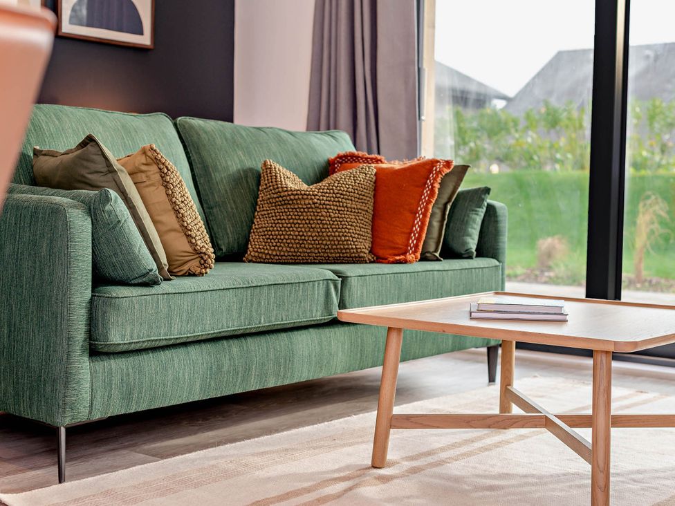 A couch with throw pillows and a coffee table in a living room at Arvor Duplex 2.0 Marhamchurch