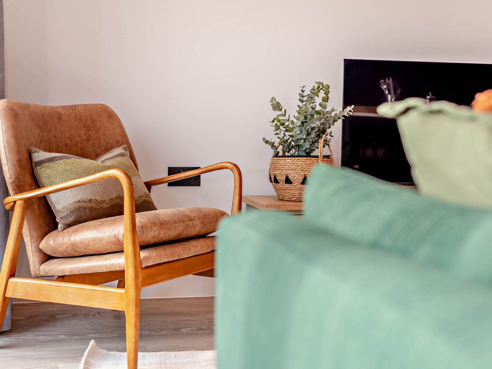 A living room with an armchair and a plant at Arvor Duplex 2.0 in Marhamchurch