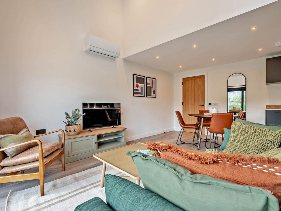A living room with a sofa and tv stand at Arvor Duplex 2.0 in Marhamchurch