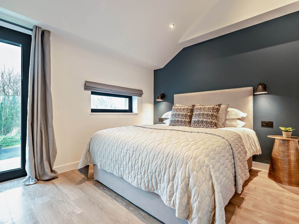 A bedroom with a bed and windows at Arvor Duplex 2.0 in Marhamchurch