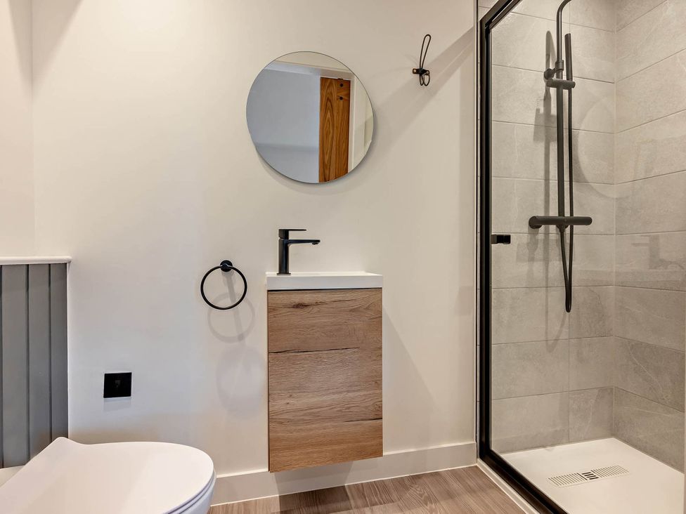 A bathroom with a sink, mirror, and shower at Arvor Duplex 2.0, Marhamchurch