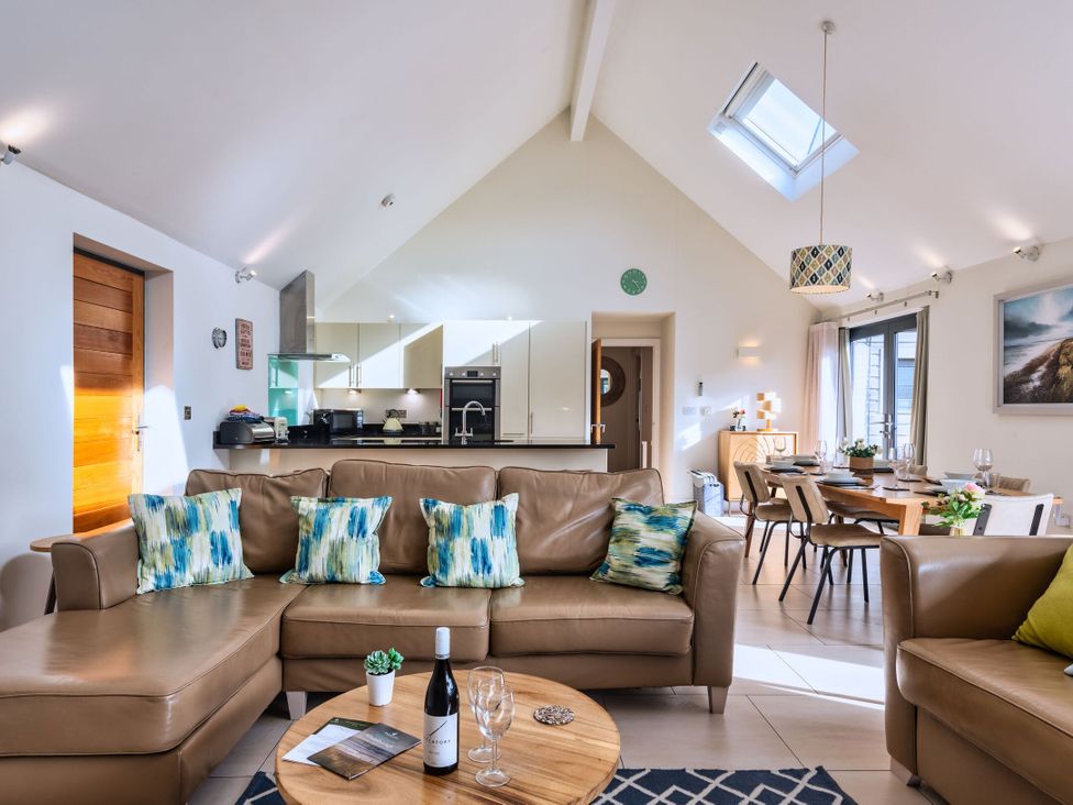A living room with a sofa and dining area at Nettlecoombe Spa in Marhamchurch