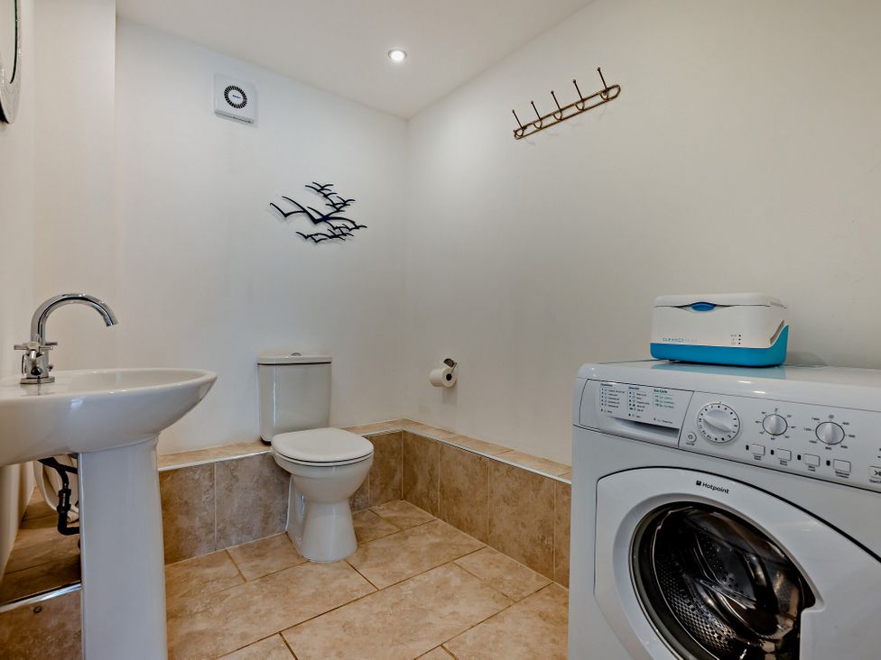 A bathroom with a sink, toilet, and washing machine at Jack's House in Marhamchurch