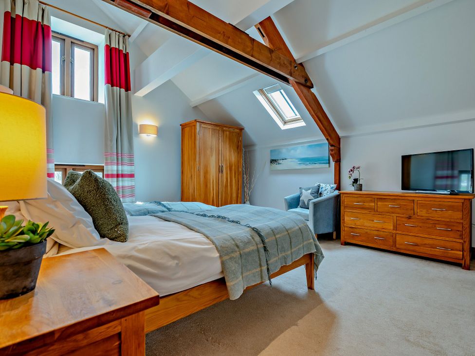 A bedroom with a bed, dresser, and television at Jack's House in Marhamchurch