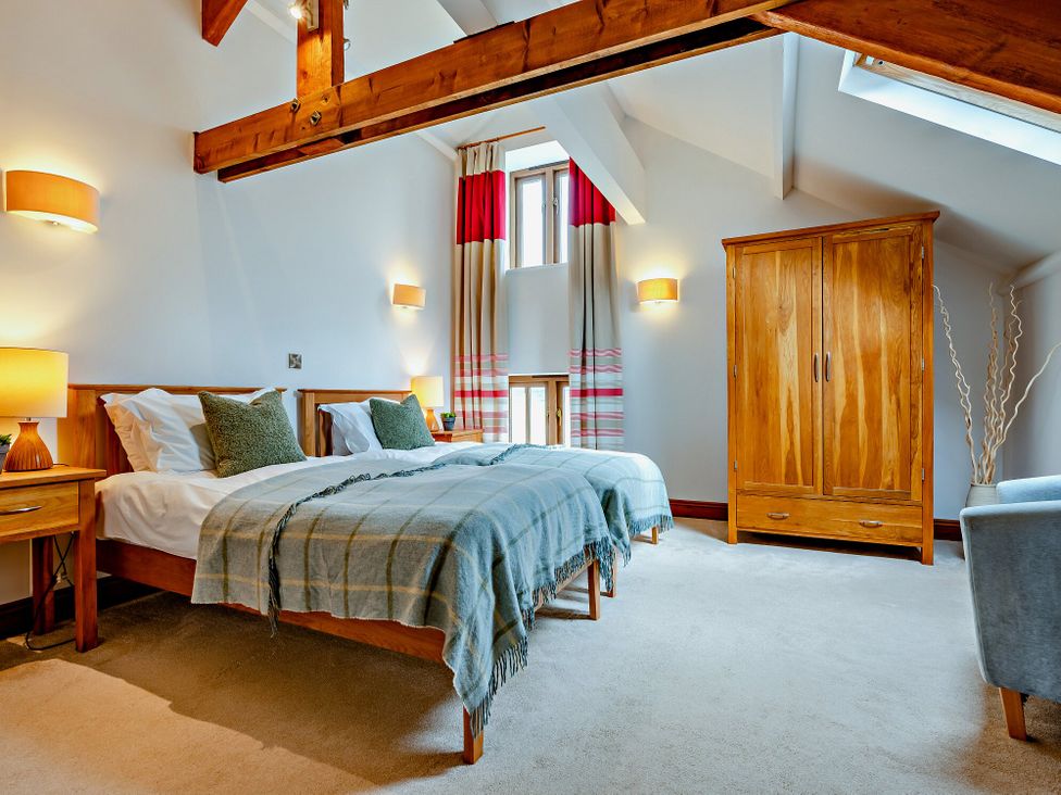 A bedroom with two beds and a wardrobe at Jack's House in Marhamchurch