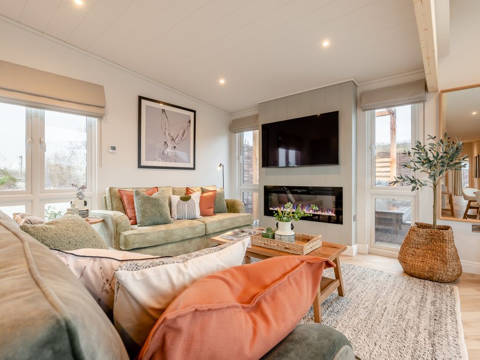 A living room with a sofa, television, and coffee table at Trelowen 4.0 Spa in Marhamchurch