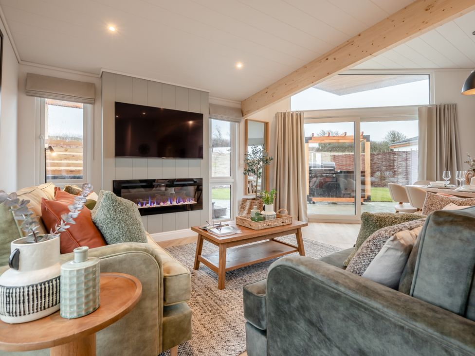 A living room with a fireplace and a television at Trelowen 4.0 Spa in Marhamchurch