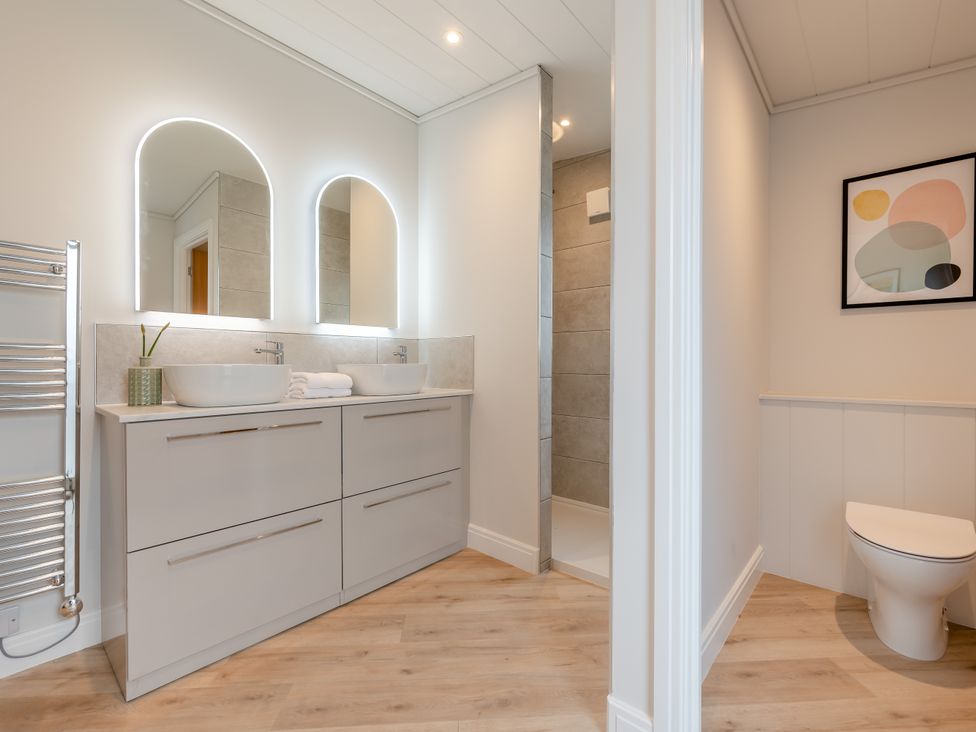 A bathroom with sinks, mirrors, shower, and toilet at Trelowen 4.0 Spa in Marhamchurch