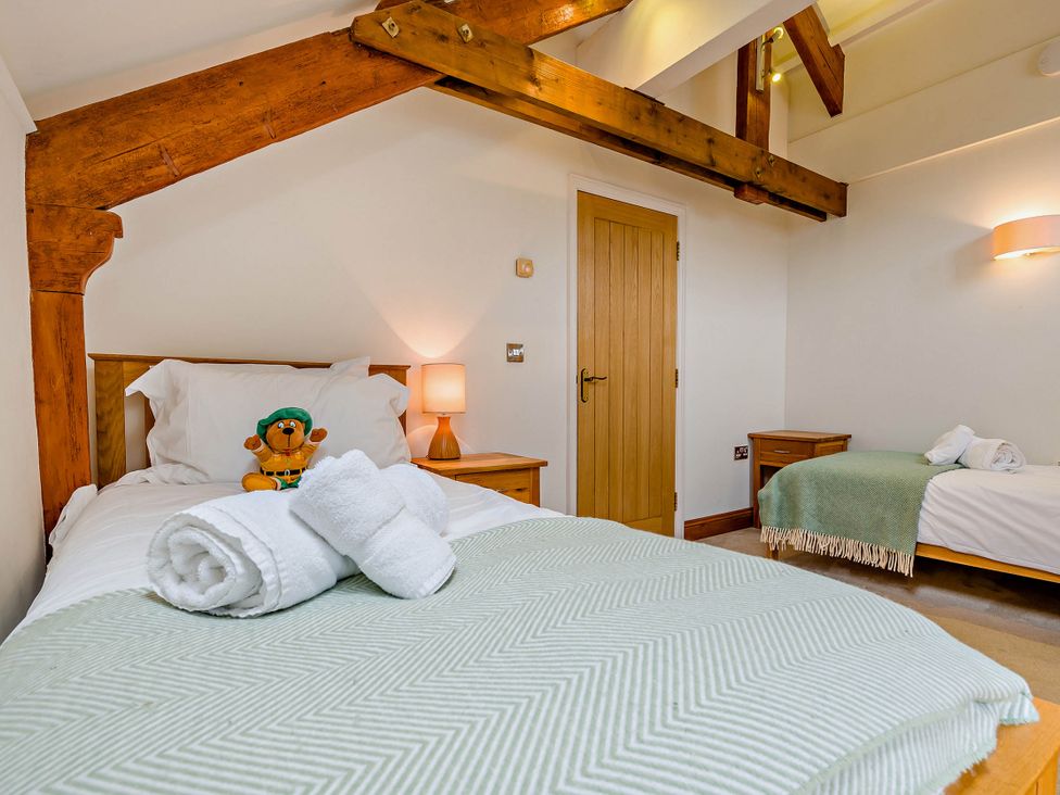 A bedroom with two beds and a teddy bear on a bed at Trelowen 4.0 Spa Marhamchurch