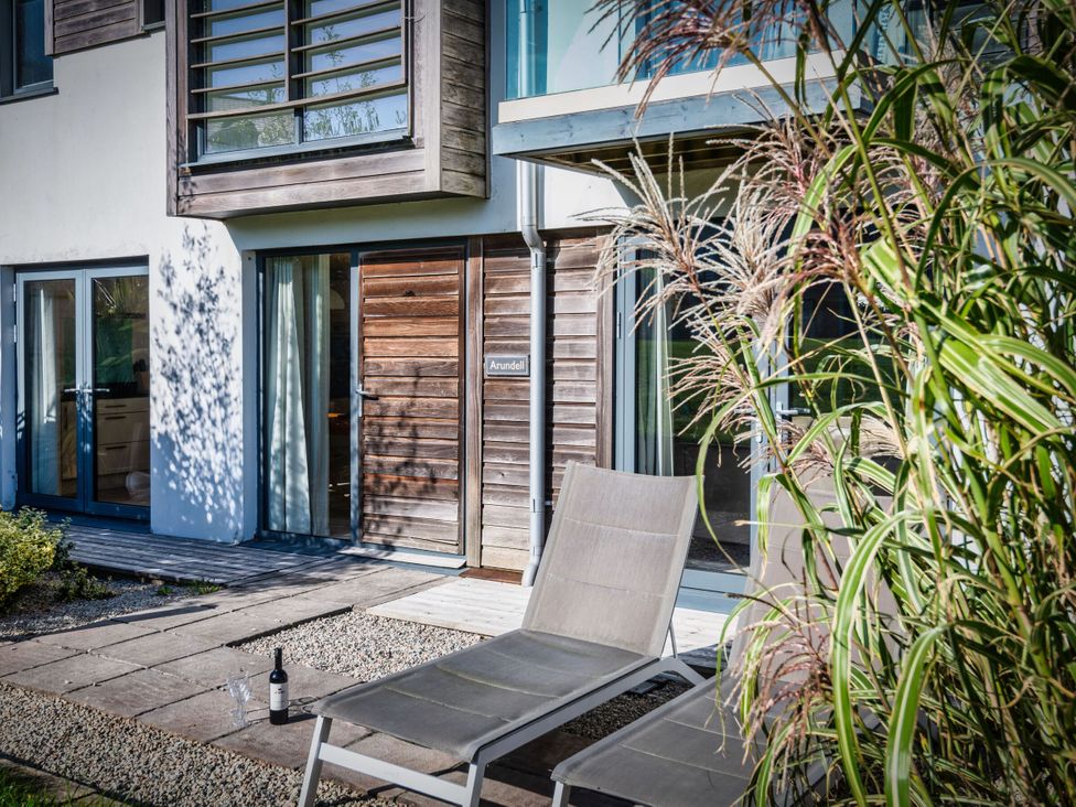 A patio area with a chair and a bottle at Arundell in Marhamchurch
