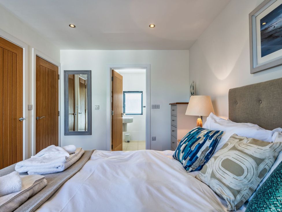 A bedroom with a bed and doors at Arundell in Marhamchurch