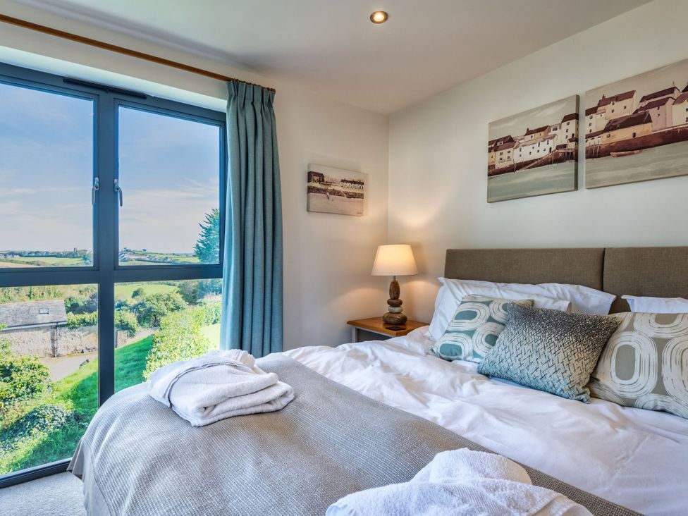A bedroom with a bed near a window at Arundell in Marhamchurch