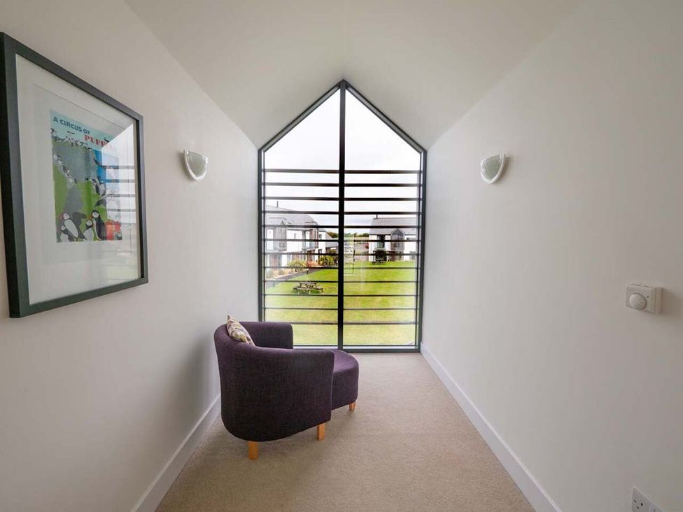 A hallway with artwork and a chair at Medlands in Marhamchurch