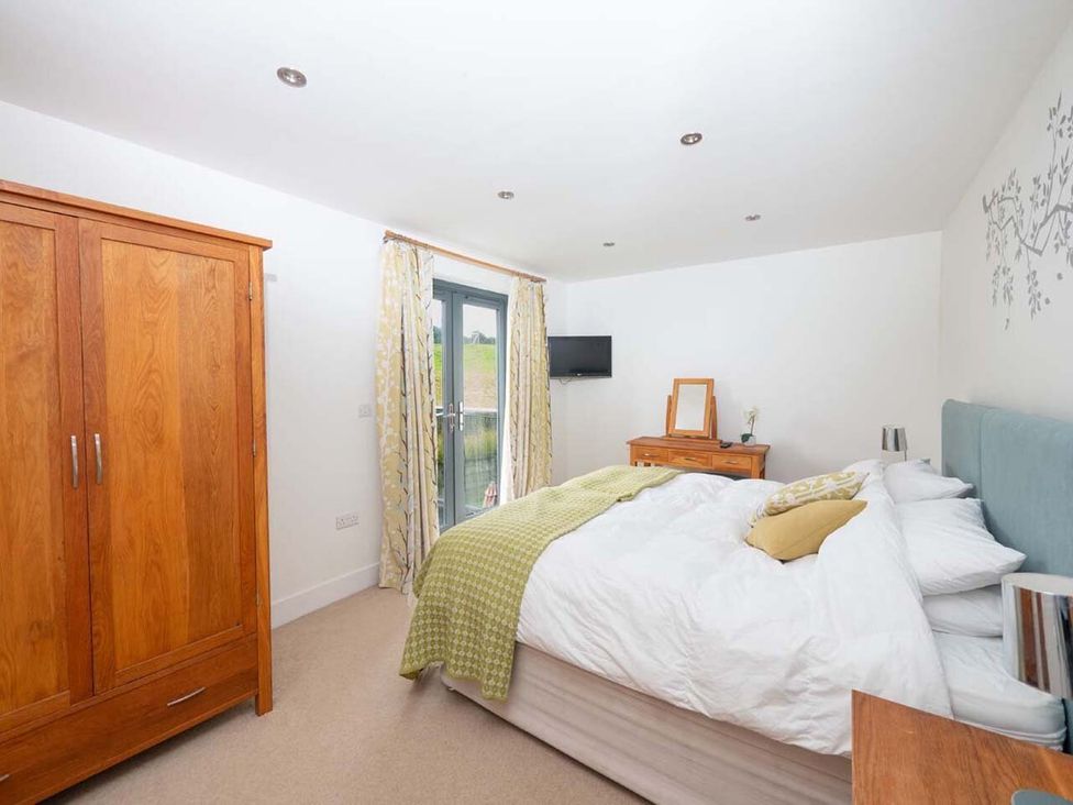 A bedroom with a bed and wardrobe at Medlands in Marhamchurch