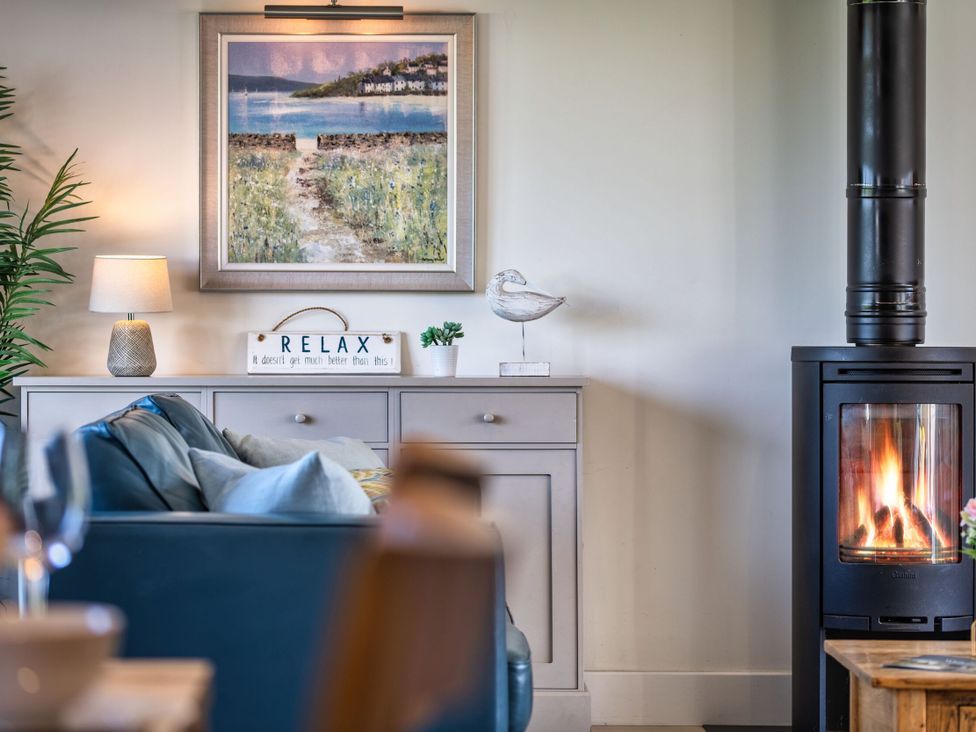 A living room with a sofa and a wood stove at Trevelyan in Marhamchurch