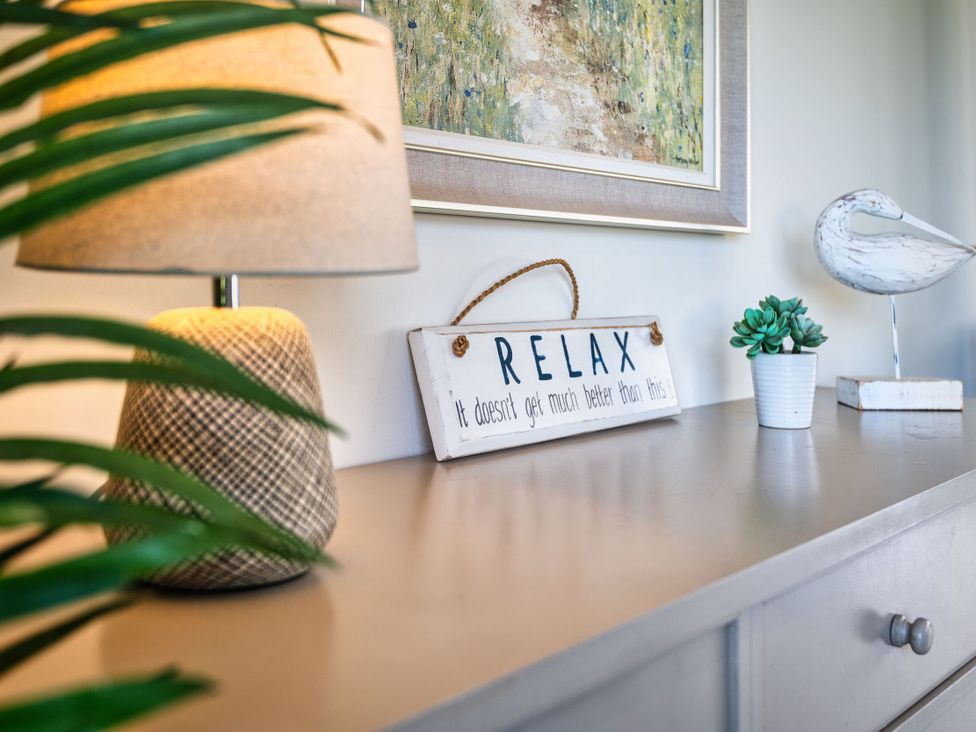 A side table with a lamp, a decorative sign, and a plant at Trevelyan in Marhamchurch