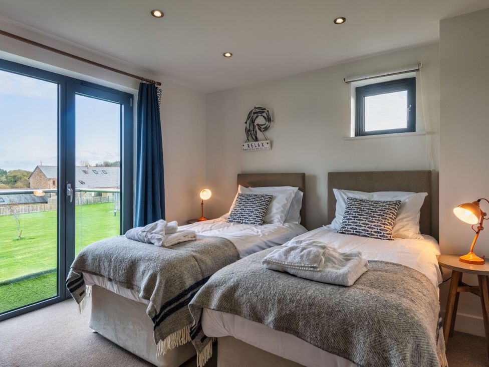 A bedroom with twin beds and a nightstand at Trevelyan in Marhamchurch