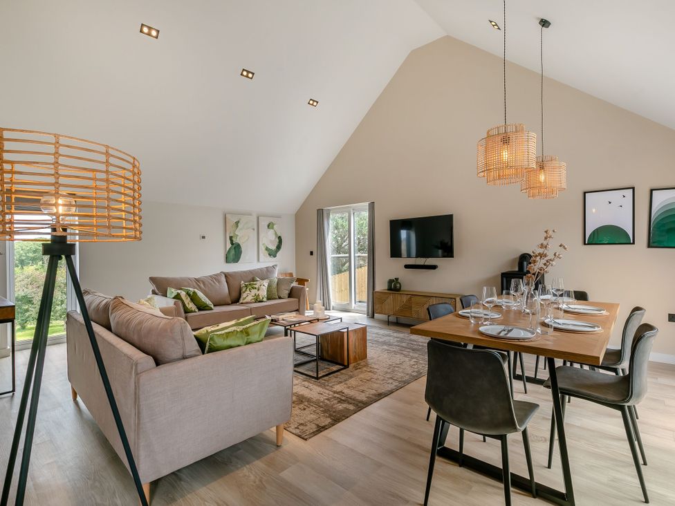 A living room with a sofa and dining area at Gwari Spa Barn 3.0 in Marhamchurch