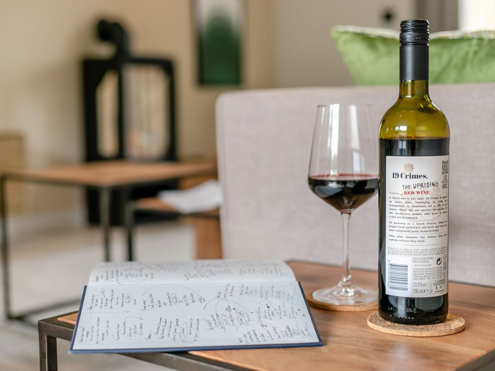 A wine bottle and glass with a menu on a table at Gwari Spa Barn 3.0 in Marhamchurch