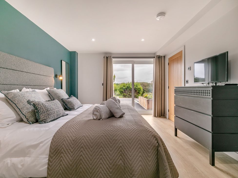 A bedroom with a bed and a television at Gwari Spa Barn 3.0 Marhamchurch