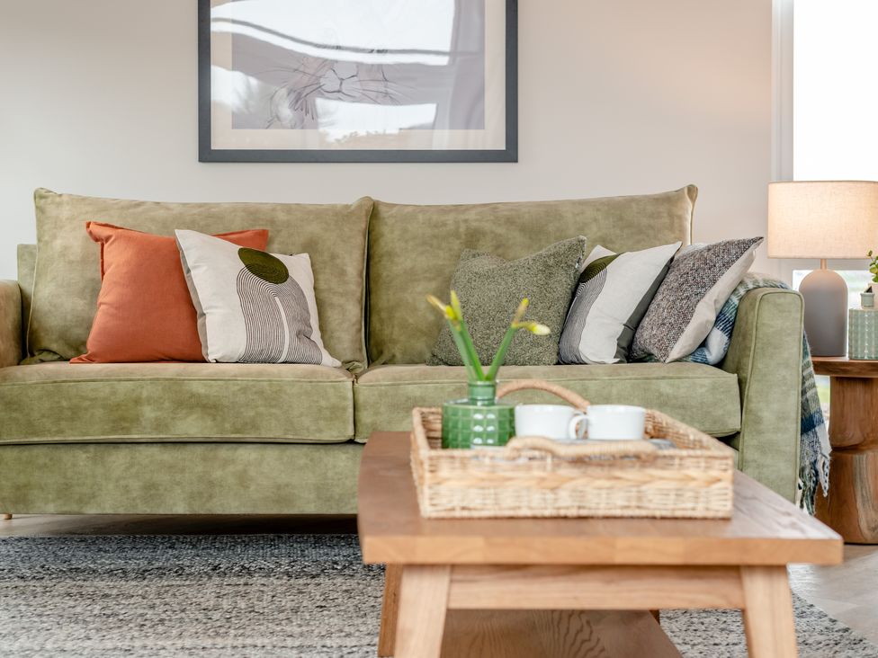 A living room with a green sofa and coffee table at Trelowen 3.0 Spa in Marhamchurch