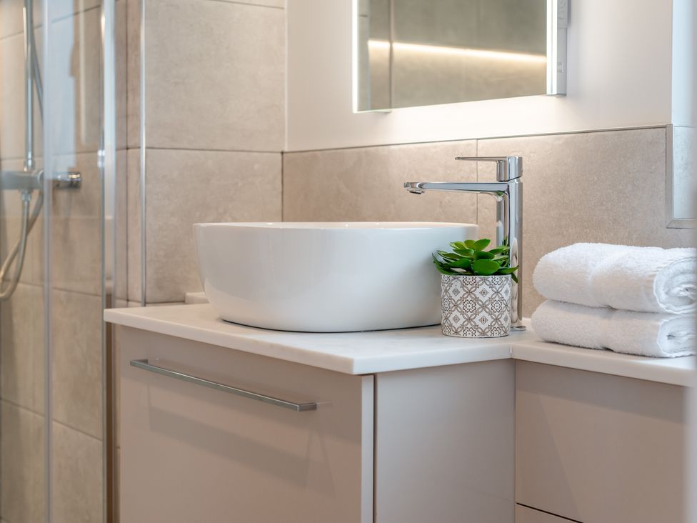 A bathroom with a sink, faucet, towels, and a plant at Trelowen 3.0 Spa, Marhamchurch