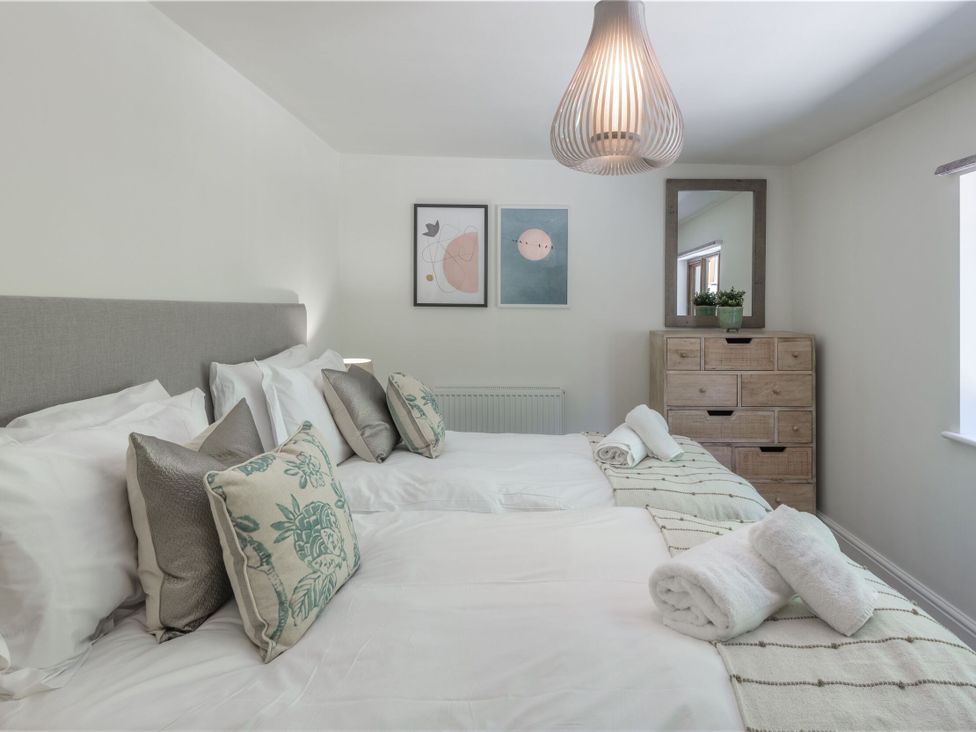 A bedroom with two beds, a chest of drawers, and wall art at Windy Hills Spa in Marhamchurch