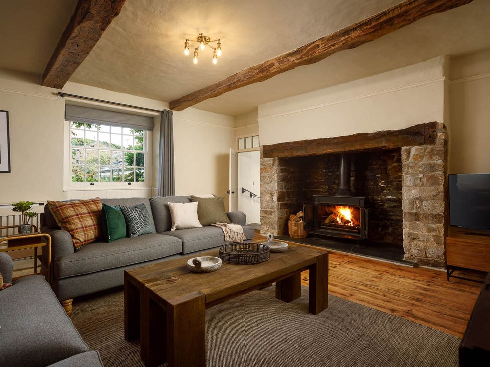 A living room with a sofa and fireplace at Whalesborough Farmhouse Spa in Marhamchurch