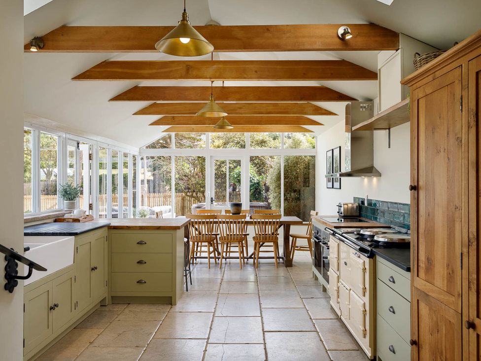 A kitchen with an island sink and wooden dining table at Whalesborough Farmhouse Spa in Marhamchurch