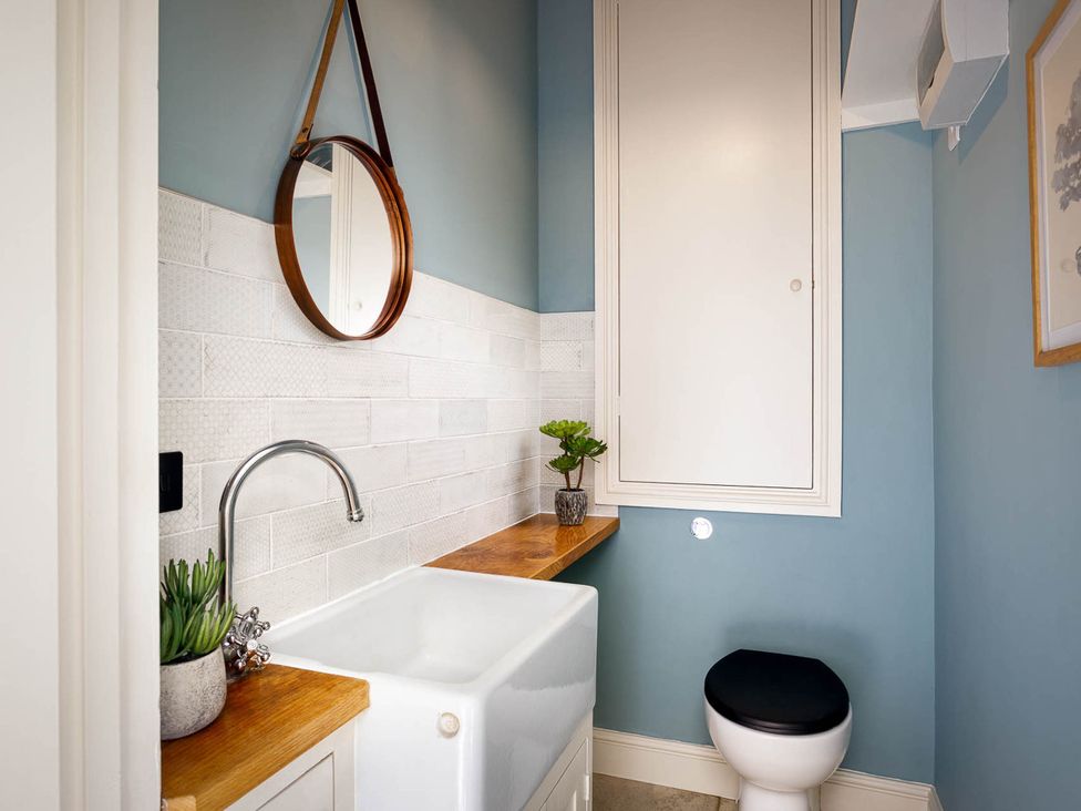 A bathroom with sink, toilet and mirror at Whalesborough Farmhouse Spa, Marhamchurch