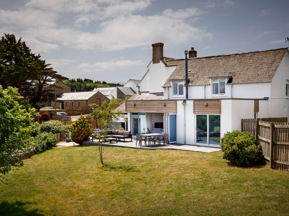 A house with outdoor seating area and garden at Whalesborough Cottage Spa in Marhamchurch