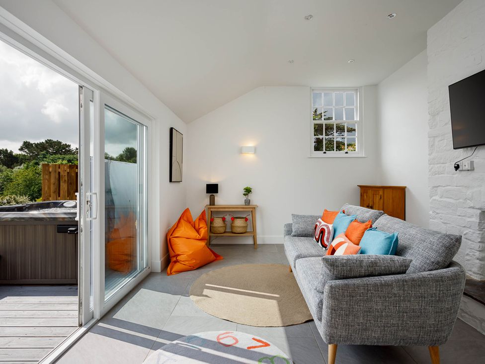 A living room with a sofa and cushions at Whalesborough Cottage Spa in Marhamchurch