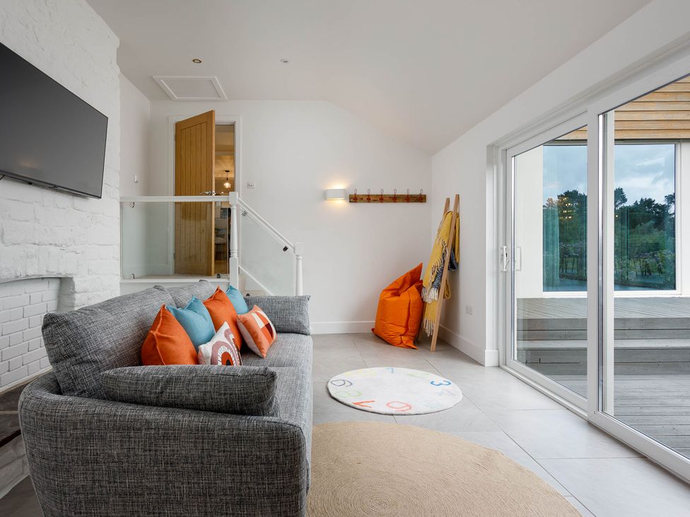 A living room with a sofa and a television at Whalesborough Cottage Spa in Marhamchurch